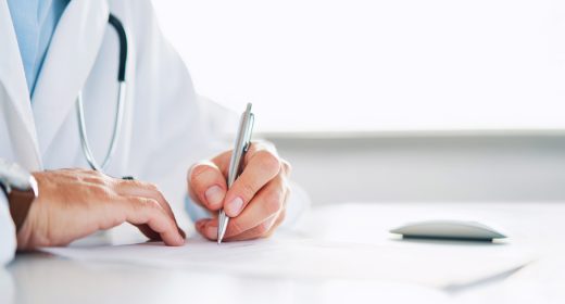 Close up of doctor signing prescription for patient