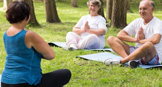 Group of elderly people meditating during outdoor yoga session in the park
